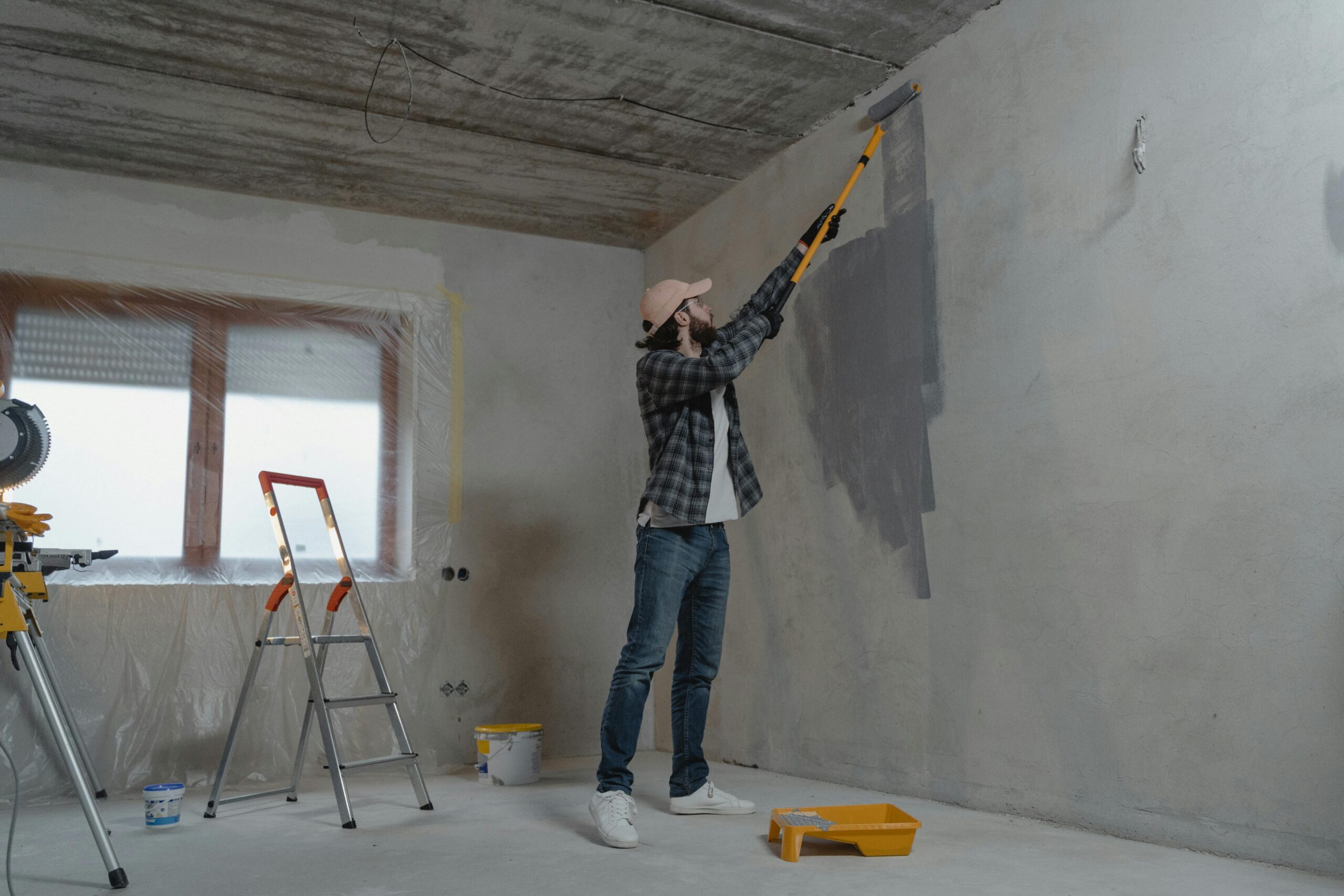 pexels-photo-6474471-6474471 A man painting an interior wall with a roller during a home renovation project.